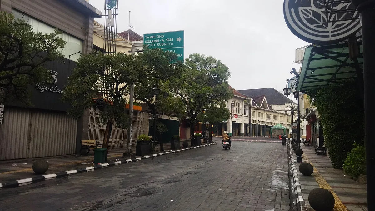Jalan Braga Bandung pada pagi hari dengan trotoar basah, deretan ruko kolonial, dan papan nama kafe