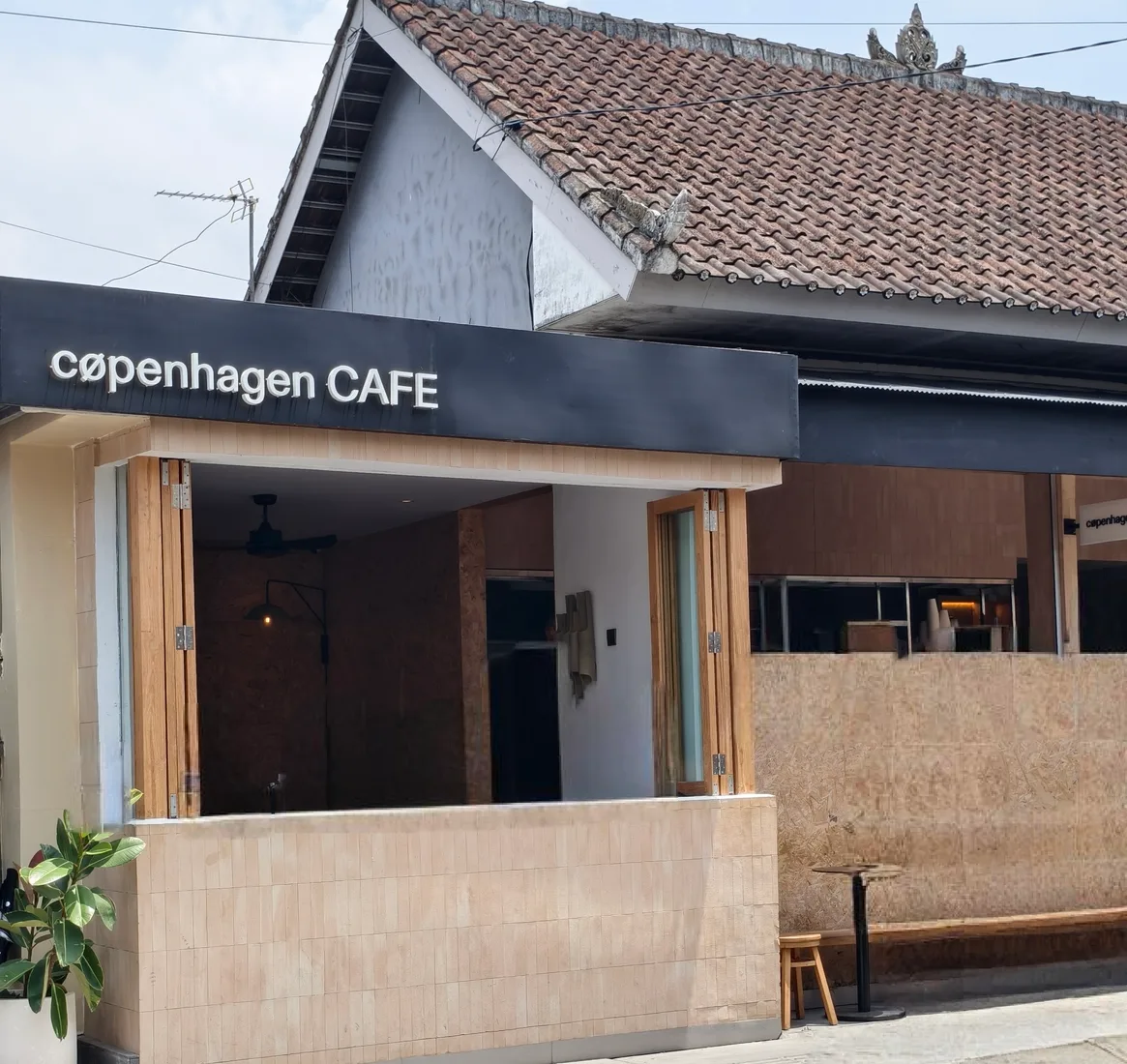 Bagian depan Copenhagen Cafe di Canggu, Bali, dengan bangku dan meja kecil di tepi jalan