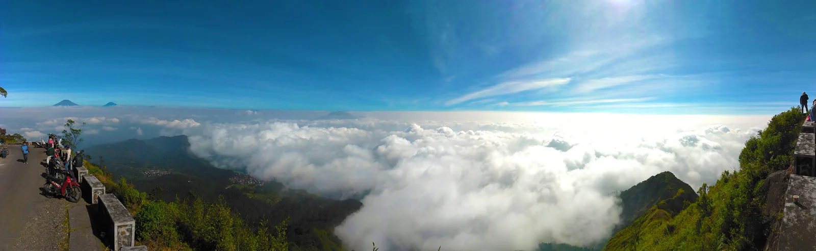Deretan sepeda motor terparkir di tepi jalan aspal menjelang puncak Gunung Telomoyo dengan lautan awan di bawahnya