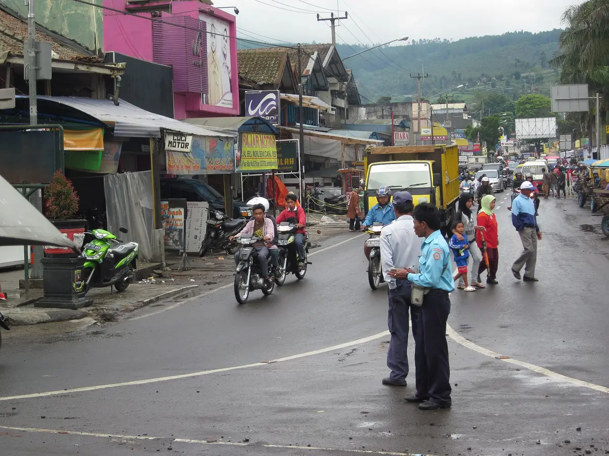 Suasana jalan di pusat Lembang dengan pengendara motor, angkutan kota, dan deretan toko di kiri kanan