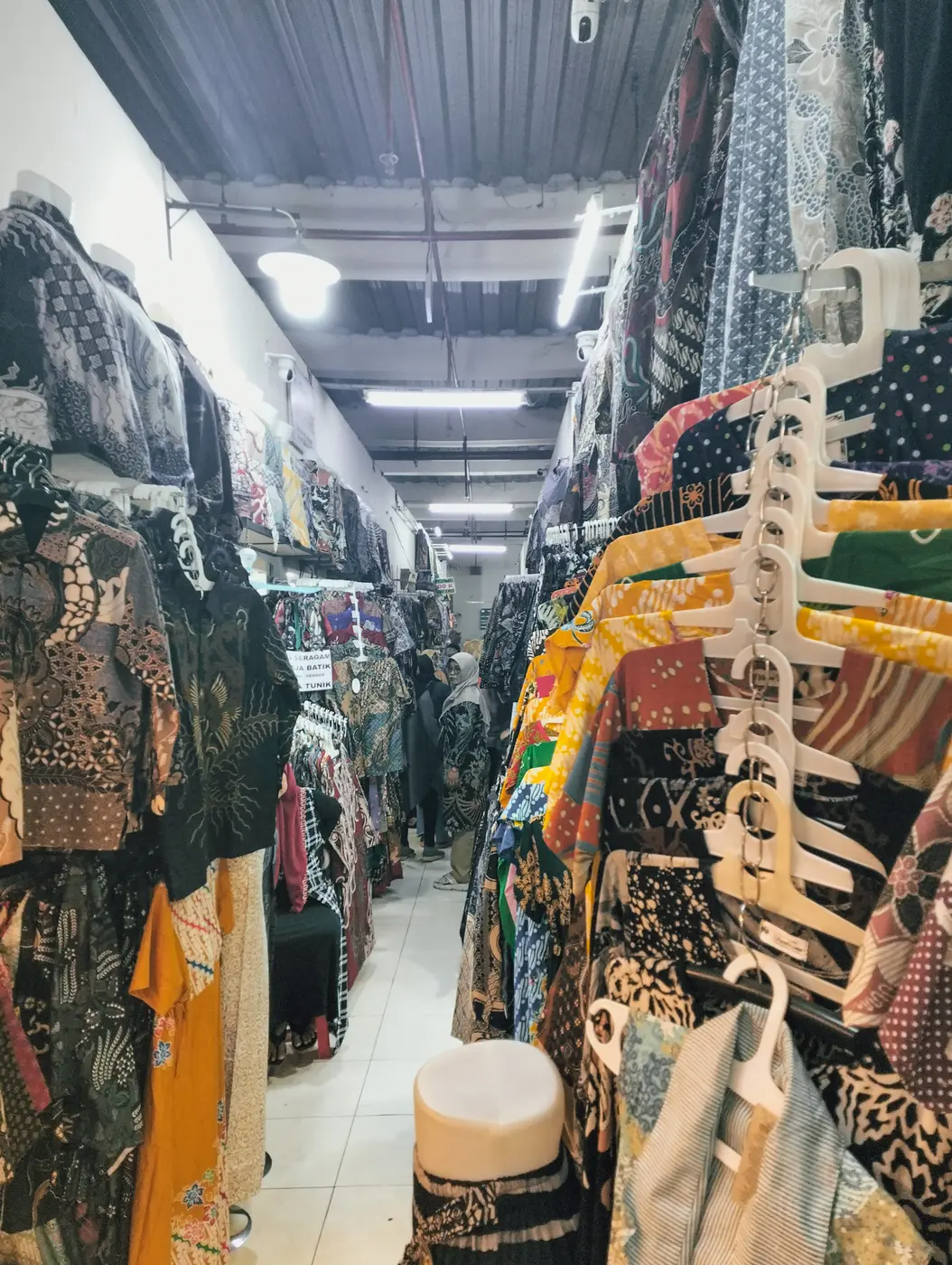 Lorong sempit di dalam Pasar Klewer penuh gantungan baju batik berwarna-warni di kanan dan kiri