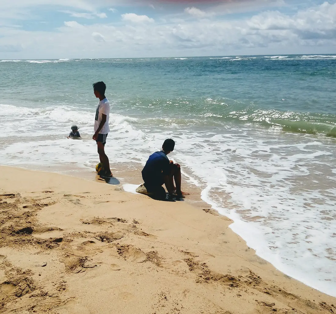 Tiga pengunjung berdiri di garis ombak Pantai Balekambang dengan buih putih Samudra Hindia