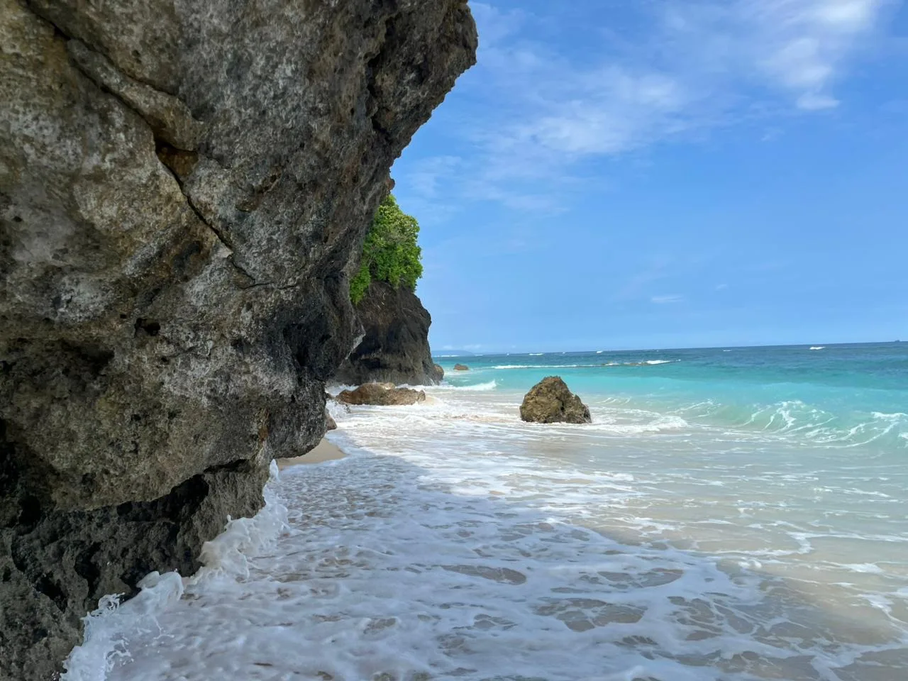 Jalur sempit di kaki tebing karang Pantai Gunung Payung dengan ombak masih menutupi pasir