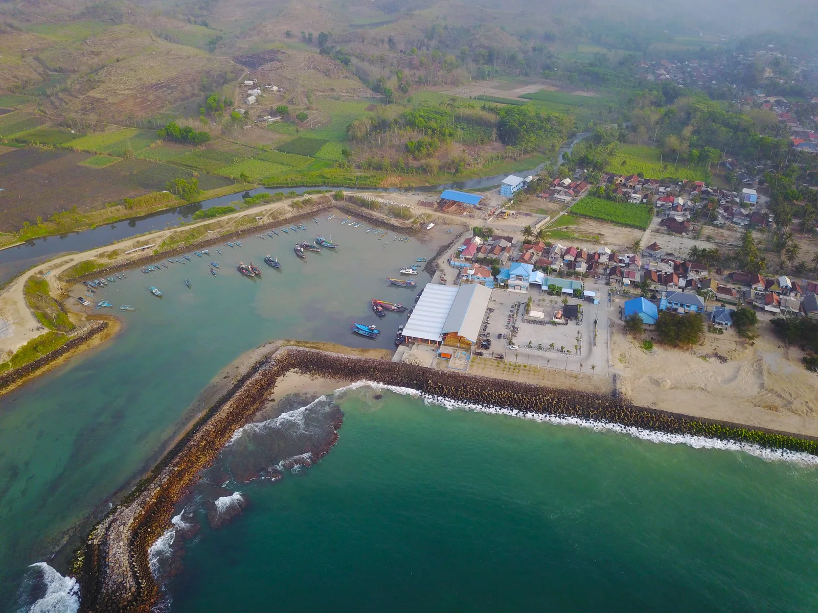 Foto udara Pelabuhan Perikanan Pantai Tambakrejo dengan pemecah ombak, kolam labuh, dan permukiman nelayan di belakangnya