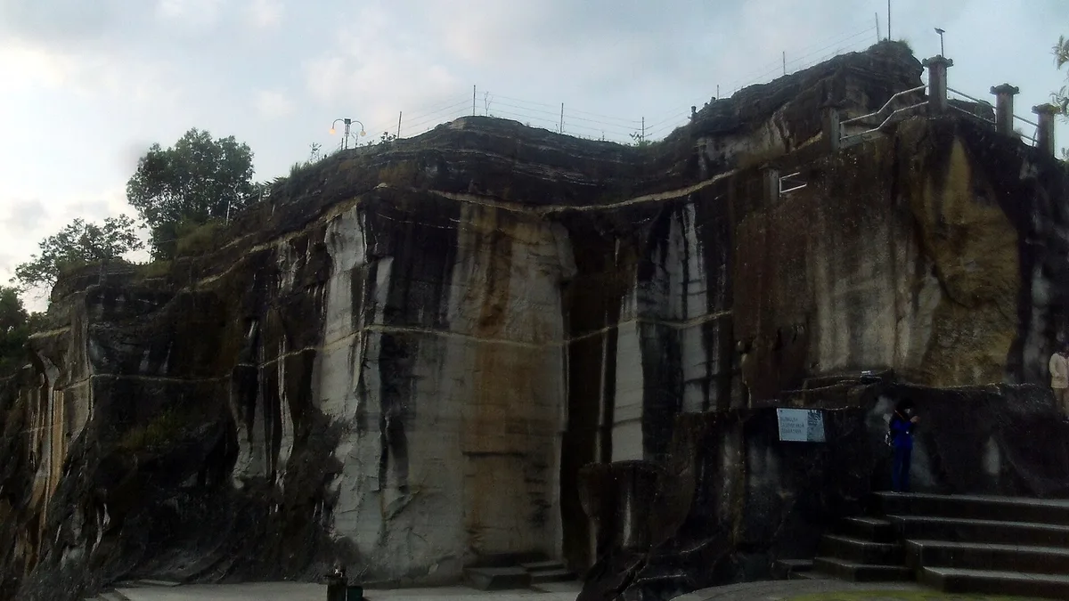 Dinding batu Tebing Breksi bekas galian di Sleman dengan pahatan vertikal dan tangga naik ke atas tebing