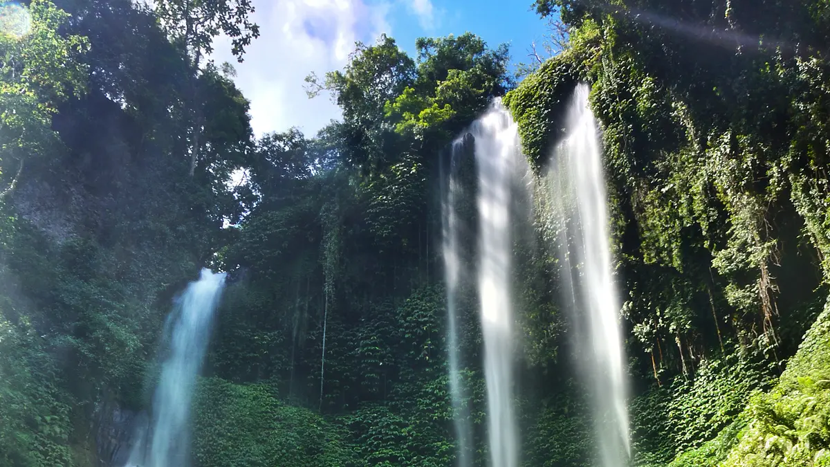 Dua tirai Air Terjun Sekumpul jatuh dari tebing berlumut hijau di Buleleng, Bali