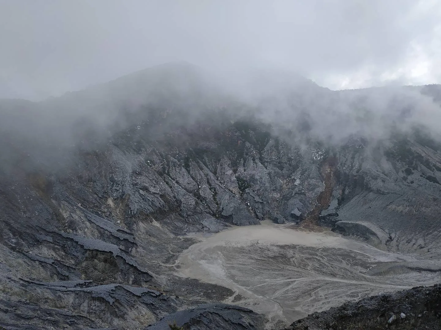Kawah Ratu di Gunung Tangkuban Perahu dengan dinding kawah berbatu abu-abu dan uap yang tertutup kabut